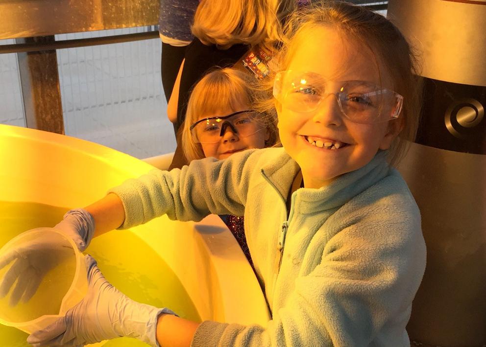 Child smiling with a bucket in hand and glasses on